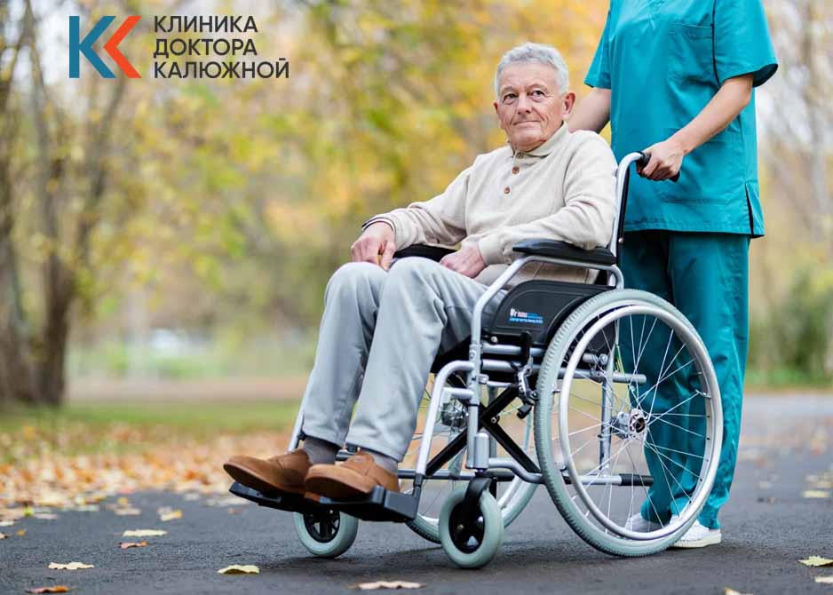 Медработник везет мужчину на кресле-коляске